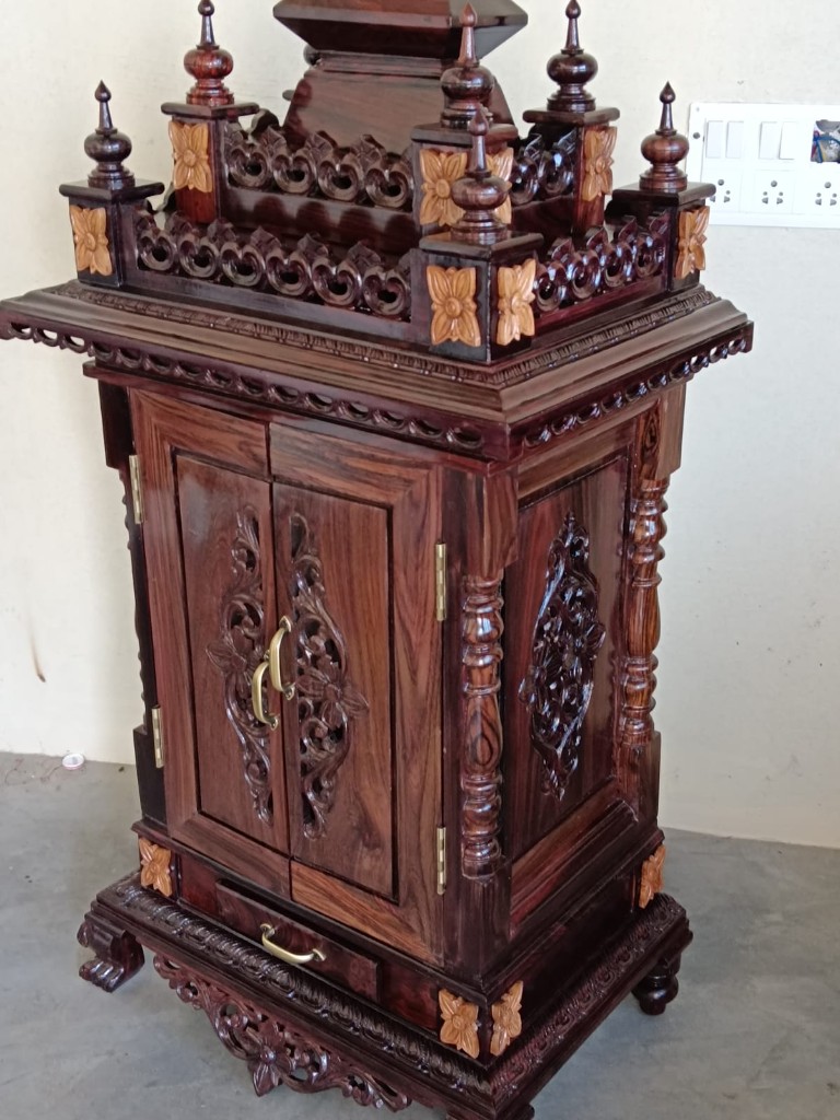 Corner of the floral inlay cabinet, showing the carved side and pale flowers on the crown